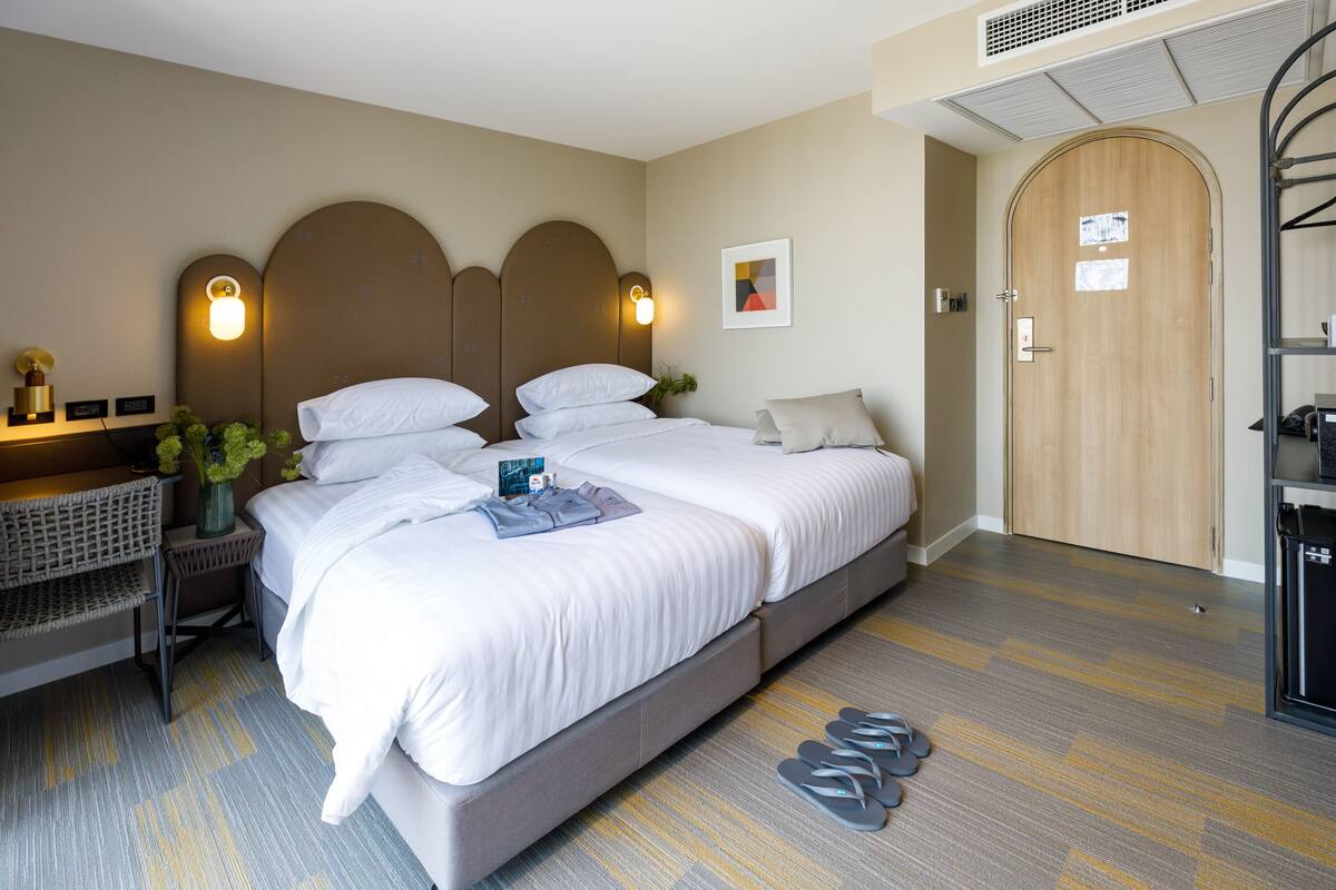 Een hotelkamer met een groot bed, een nachtkastje met lamp, een zithoekje en een kledingkast.