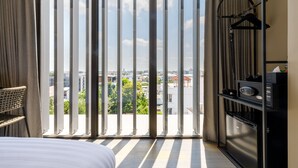 Quarto de hotel com uma grande porta de correr de vidro que dá para uma varanda, uma cama, um guarda-roupa e uma área de trabalho.