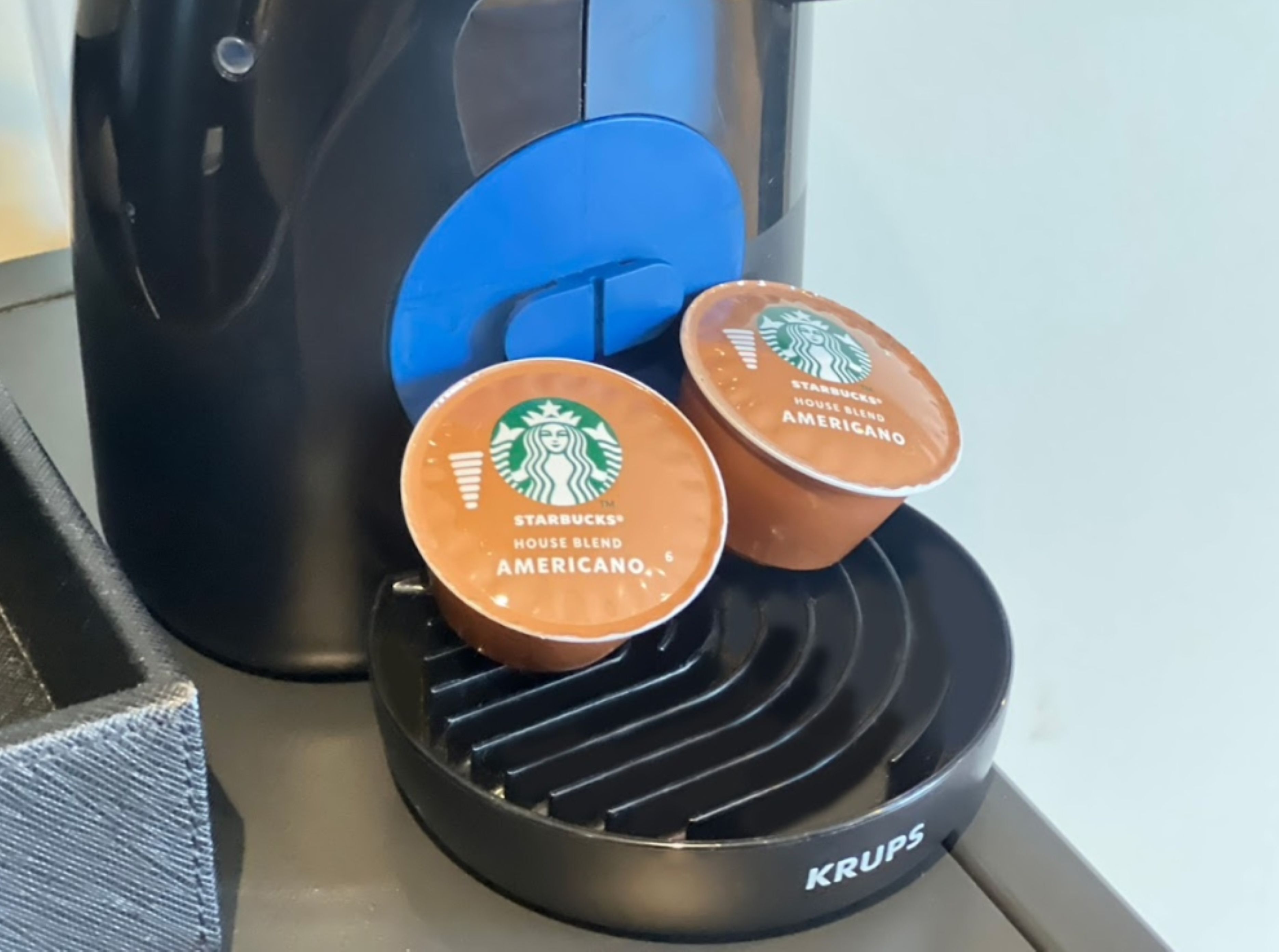 Uma cafeteira Krups com duas cápsulas de Starbucks Americano em sua base aquecida.
