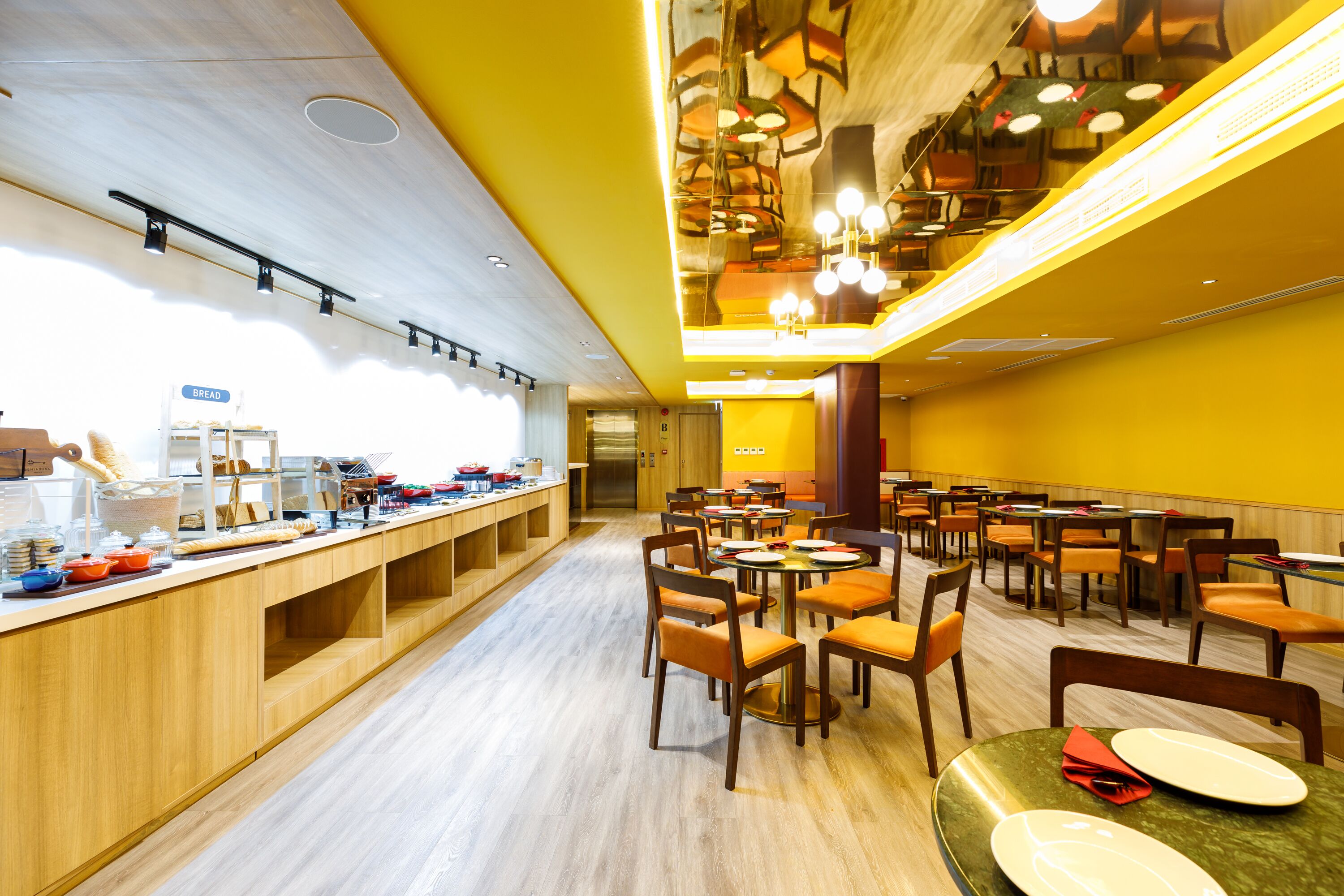 A bright, modern dining area with wooden counters and orange chairs.