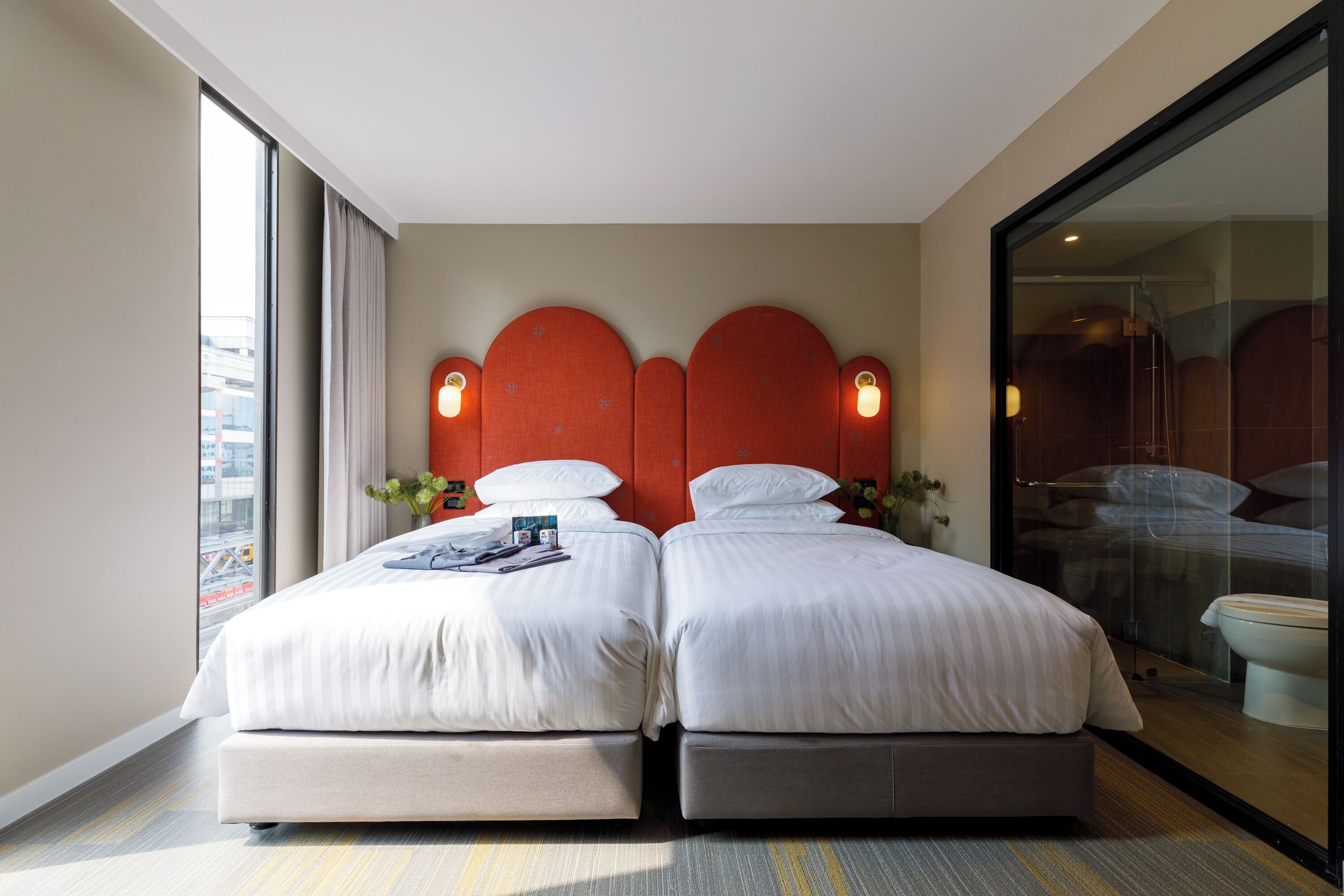 A double room with two beds, a large window, and a view of the city.