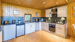 Une cuisine avec des murs en bois, un pare-feu en carrelage, un four à micro-ondes, un évier et un lave-vaisselle.