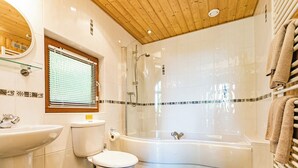 Une salle de bain moderne équipée de toilettes, d’un lavabo et d’une douche séparée par une paroi en verre.