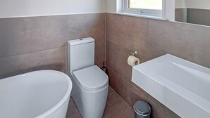 Une salle de bain équipée de toilettes, d’un bidet et d’une baignoire.