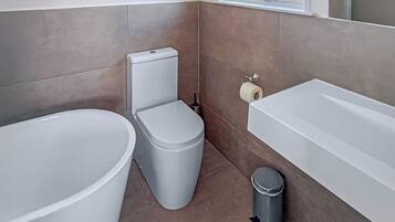 A bathroom with a toilet, bidet, and bathtub.