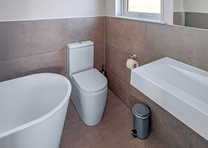 Een badkamer met toilet, bidet en bad.