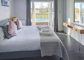 A bedroom with a bed, a desk, and a view of a backyard. - 3 bedroom accommodation in Newbury (Newbury)