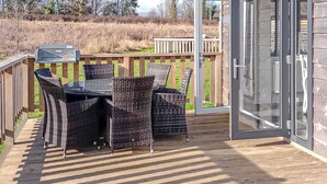 Une terrasse extérieure avec une table et des chaises, un barbecue et une plateforme en bois.