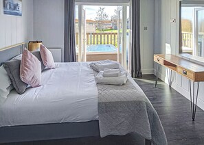 A bedroom with a bed, a desk, and a view of a backyard.