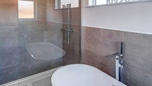 A modern bathroom with a freestanding bathtub, a glass-enclosed shower, and a vanity with a mirror. - 3 bedroom accommodation in Newbury (Newbury)