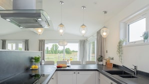 A modern kitchen with a central island, built-in appliances, pendant lighting, and a view of the outdoors.