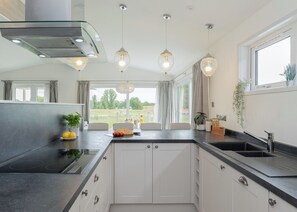 A modern kitchen with a central island, built-in appliances, pendant lighting, and a view of the outdoors.