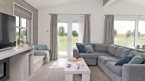 A modern living room with a sofa, a coffee table, a TV, and a view of the outdoors.