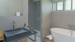 A modern bathroom with a freestanding bathtub, a glass-enclosed shower, and a vanity with a sink and towel rack.