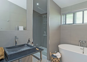 A modern bathroom with a freestanding bathtub, a glass-enclosed shower, and a vanity with a sink and towel rack.