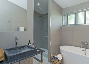 A modern bathroom with a freestanding bathtub, a glass-enclosed shower, and a vanity with a sink and towel rack.
