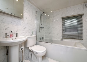 A bathroom with a marble sink, toilet, and glass-enclosed shower.