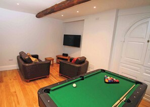 Ein Billardtisch mit Kugeln, zwei Sofas, ein Fernseher und ein Holzbalken an der Decke.