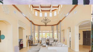 A spacious living room with a high ceiling, large windows, and a chandelier. - 3 Bedroom 2 Bath Condo Disney area 8601 (Orlando)