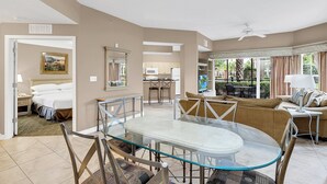 A spacious living area with a glass dining table, comfortable seating, a kitchenette, and a bedroom with a bed and nightstand. - 3 Bedroom 2 Bath Condo Disney area 8601 (Orlando)