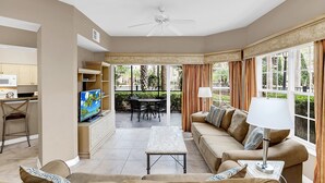 A living room with a sofa, TV, and a dining area with chairs and a table. - 3 Bedroom 2 Bath Condo Disney area 8601 (Orlando)