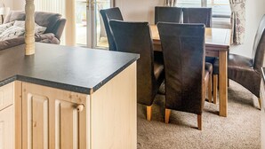 A kitchen with a wooden countertop, a dining table with chairs, and a view of the outdoors through a window.