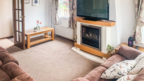 A living room with a fireplace, a sofa, a coffee table, and a television.