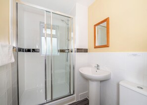 A bathroom with a glass-enclosed shower, a white sink, and a mirror on the wall.