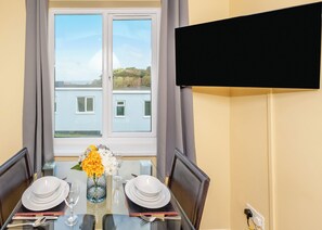 A dining table set for two with plates, glasses, and a vase of flowers.