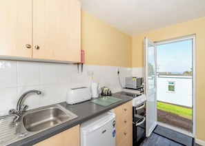 A compact kitchen with a sink, toaster, kettle, and a small oven.
