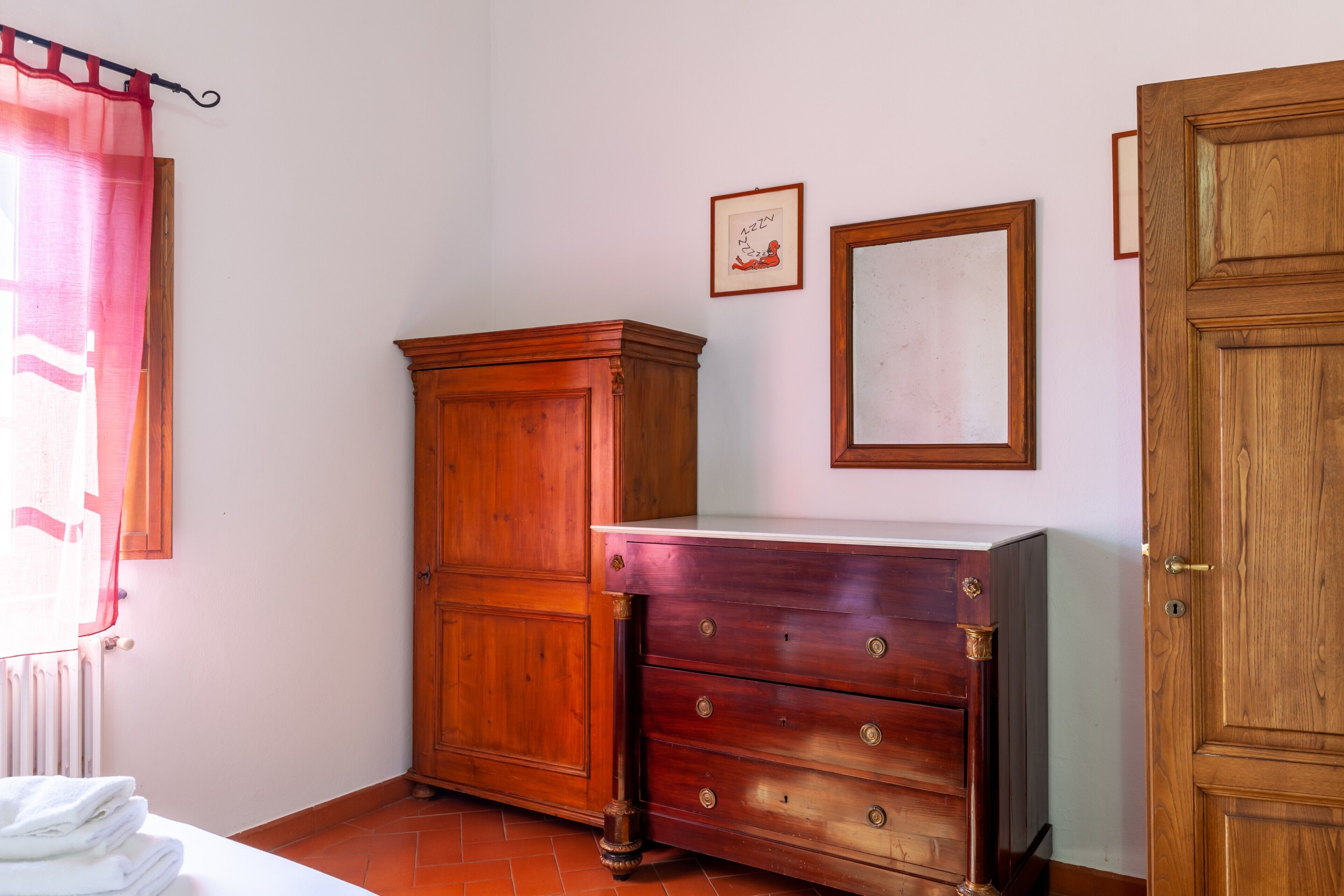A room with a wooden wardrobe, a dresser, and a radiator.