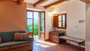 A room with a sofa, a bench, a wooden cabinet, and a window with a view of greenery. - Villa 'Podere Par di Rota' with Pool, Terrace and Wi-Fi (Calci)