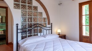 A bedroom with a bed, a nightstand, a lamp, a window, and a wall with decorative panels. - Villa 'Podere Par di Rota' with Pool, Terrace and Wi-Fi (Calci)
