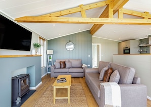 A cozy living room with a sofa, a coffee table, a TV, and a fireplace.