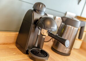 Une machine à café dotée d’un levier et d’un bouton, d’une cafetière en acier inoxydable et d’une surface en bois.
