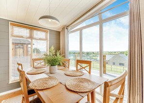 A dining area with a wooden table, woven placemats, and a potted plant.