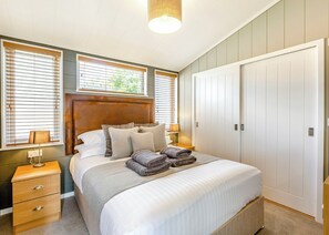 A bedroom with a bed, bedside tables, a wardrobe, and windows with blinds.