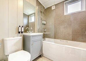A bathroom with a toilet, a sink with a mirror, a shower, and a bathtub.