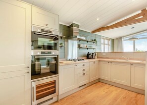 Eine moderne Küche mit weißen Schränken, einem eingebauten Backofen, einer Holzarbeitsplatte und einem Fenster für natürliches Licht.