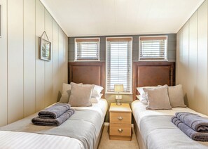 Ein Schlafzimmer mit zwei Betten, einem Nachttisch und einem Fenster mit Jalousien.