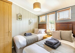 Ein Schlafzimmer mit zwei Betten, einem Holzschrank und einer Pendelleuchte.