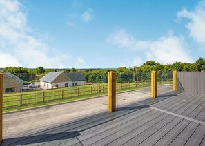 A wooden deck with a view of a rural landscape, including a barn and a fence. - Luxurious lodge with vaulted ceilings and a welcoming feature fireplace. (Glastonbury)