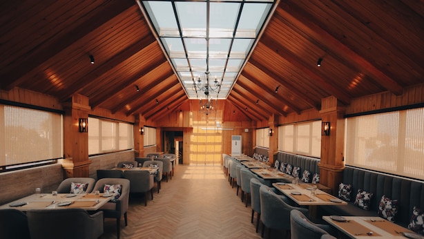 A long dining hall with wooden walls and a high ceiling, featuring tables and chairs arranged for dining. - Clarks Inn Express Dehradun  (Dehradun)