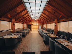 A long dining hall with wooden walls and a high ceiling, featuring tables and chairs arranged for dining. - Clarks Inn Express Dehradun  (Dehradun)