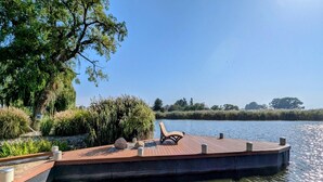A wooden dock with a bench, surrounded by greenery and a calm body of water. - Tranquil Waterside Hideaway (Usedom)