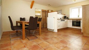 Cocina compacta con comedor, que incluye un refrigerador blanco, estufa y un lavamanos pequeño.
