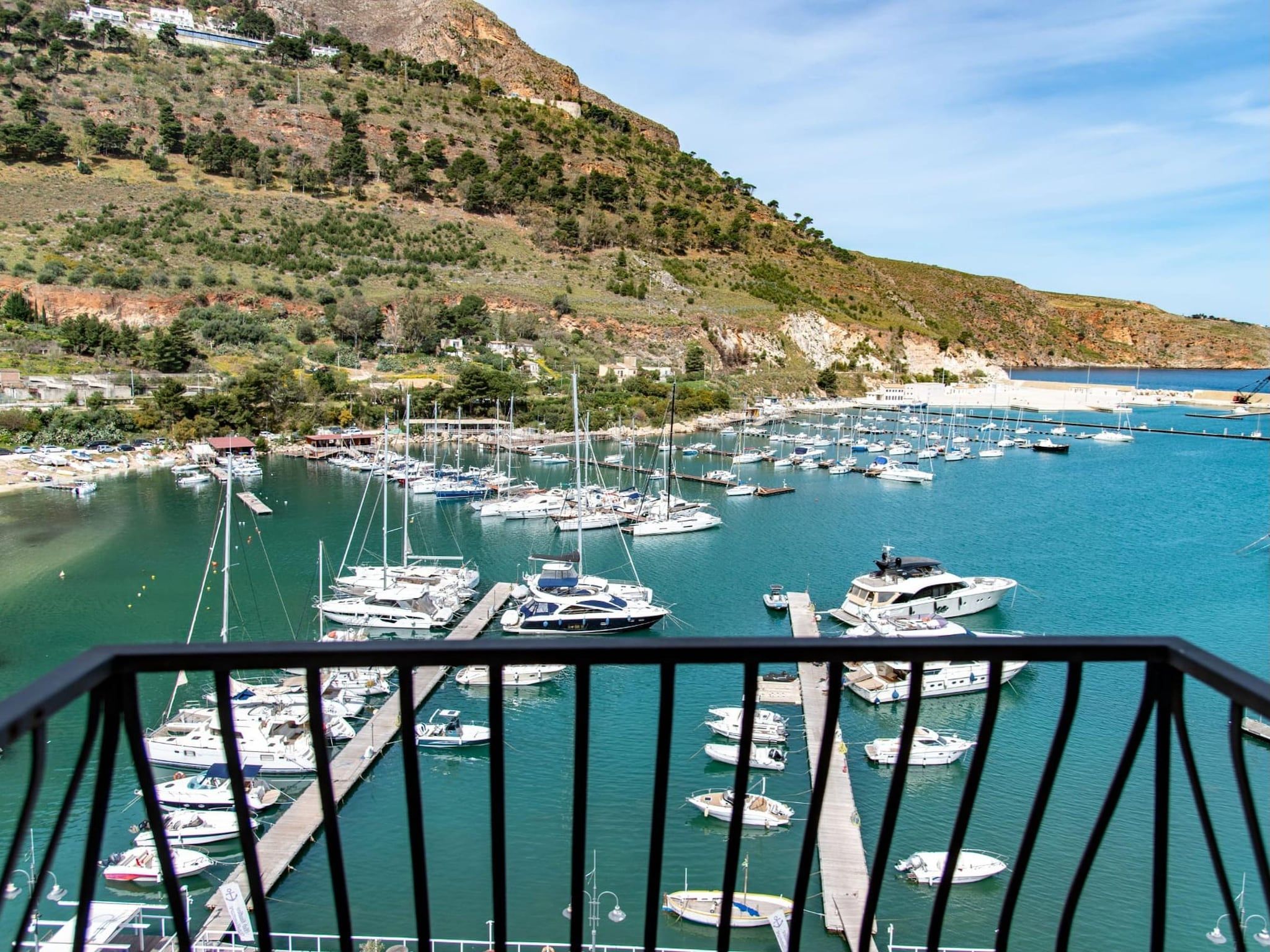 A marina with numerous boats docked, surrounded by hills and a clear sky.