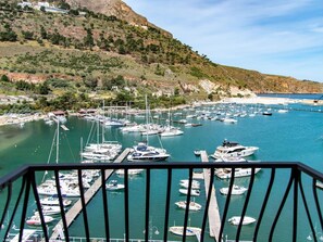 A marina with numerous boats docked, surrounded by hills and a clear sky.