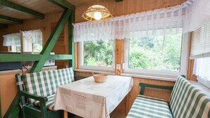 L’intérieur chaleureux d’un chalet avec une table, des bancs et une fenêtre donnant sur un paysage verdoyant.