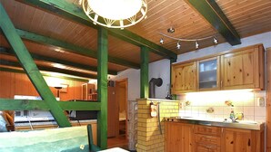 Une cuisine rustique avec des armoires en bois, un mur en briques et un ventilateur de plafond.